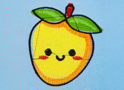 Machine embroidery design of a cute yellow mango with green leaves on blue fabric, showing registration issues and shifting caused by missing underlay.