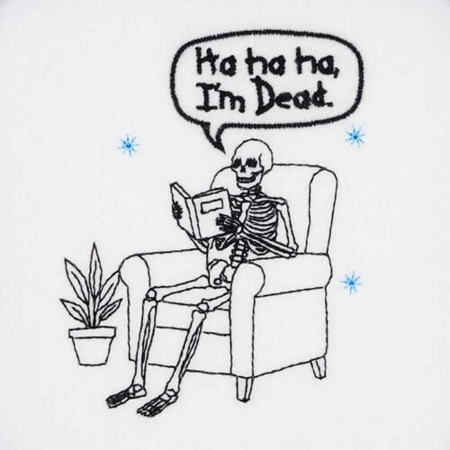 Skelly reading a book embroidery design