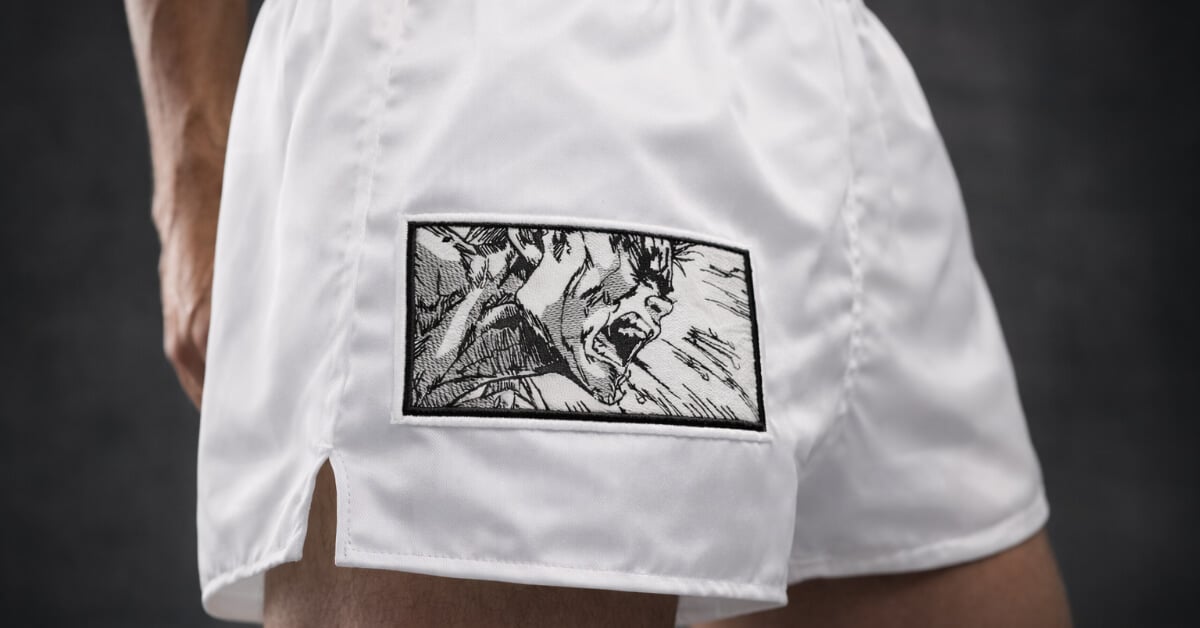 Seinen-style anime embroidery design with detailed line art stitched on Muay Thai shorts