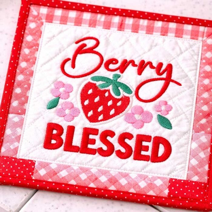 SD_SF_03_QuiltSquare | Embroidery Legacy Quilted square with embroidered 'Berry Blessed' and a strawberry motif on pink patchwork fabric.