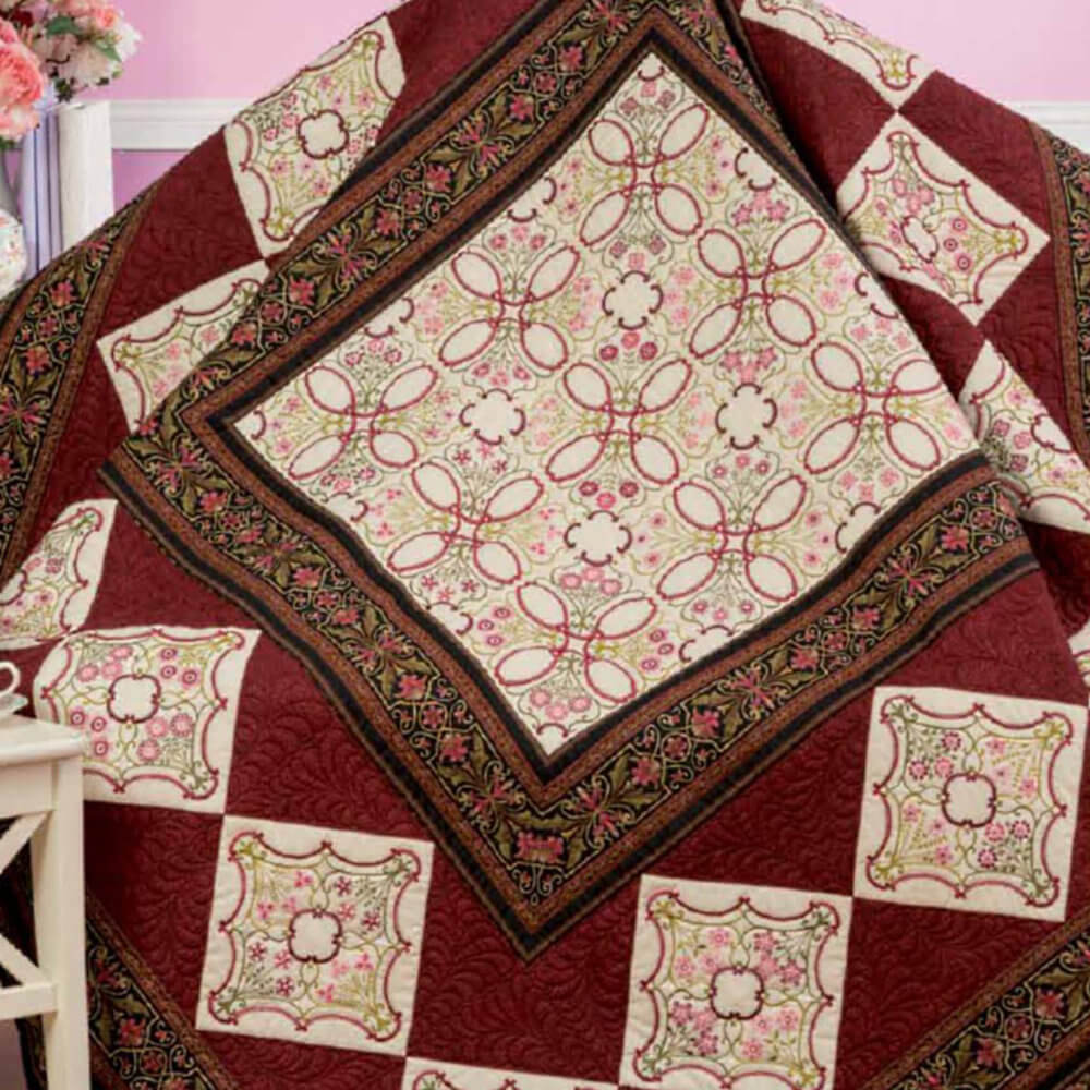 Artboard43_2 Quilt draped with cream, pink, and burgundy squares featuring floral and geometric patterns.
