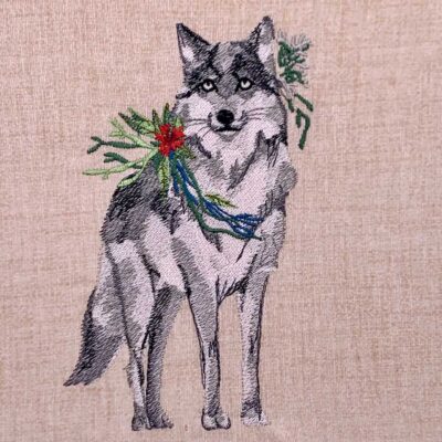 Embroidered gray wolf with a red flower bouquet and green leaves draped around its neck on beige fabric background