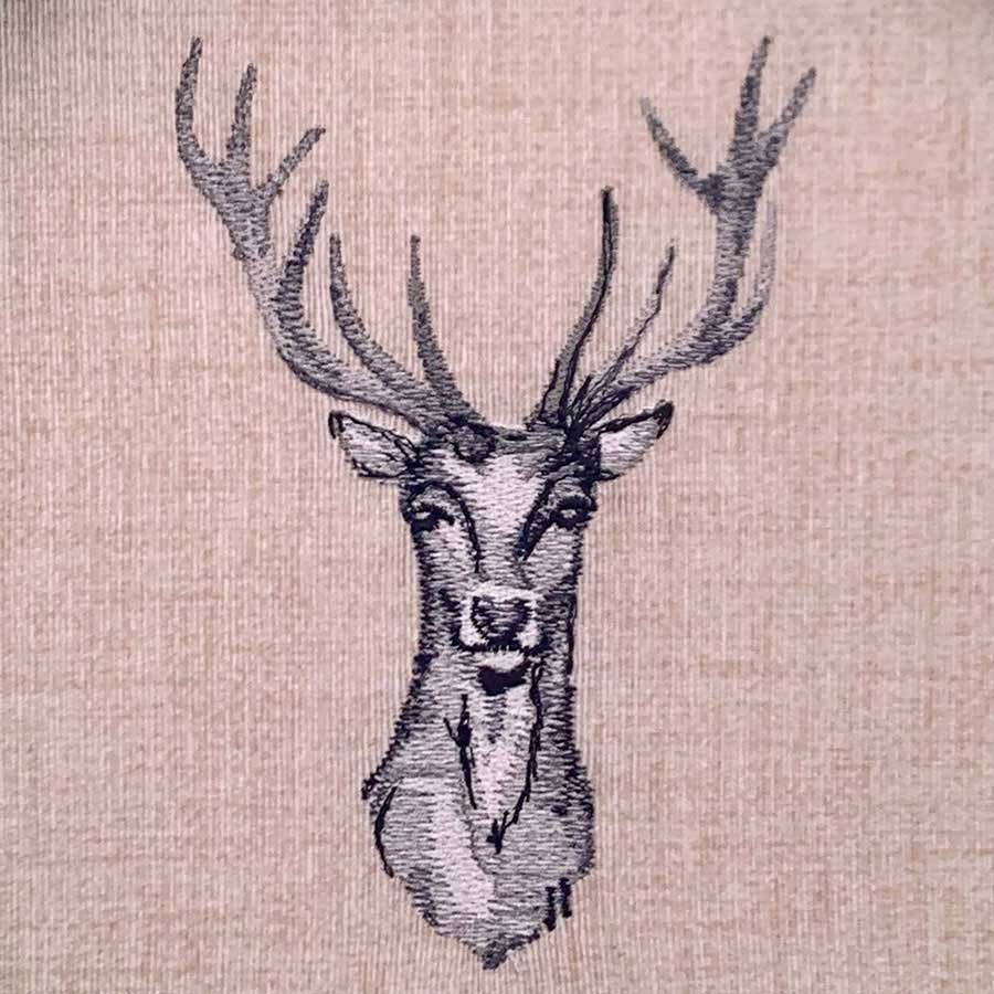 Embroidery of a deer's head with large antlers on beige fabric, in gray and black threads