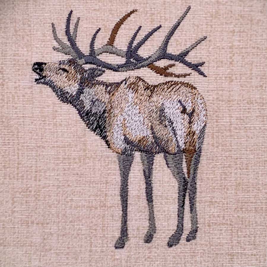 Embroidered image of a deer with large antlers on beige fabric background