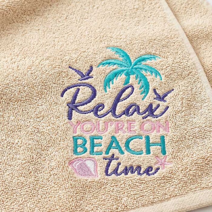 SDSB_RelaxBeachTime_BeachTowel | Embroidery Legacy Beige towel with teal embroidered palm tree and the pastel pink/teal phrase 'Relax You're on Beach Time'.