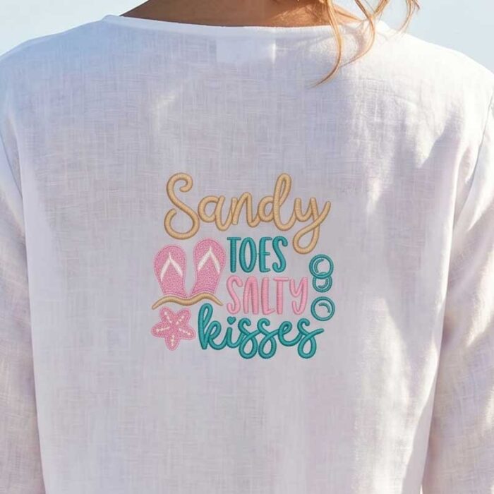 SDSB_SandyToesCoverup | Embroidery Legacy Back of a person wearing a white shirt with pastel embroidered beach slogan: 'Sandy Toes, Salty Kisses' with flip-flop and flower icons.
