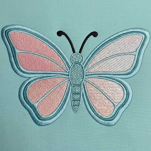 ShonteS_VideoThumbail Embroidered butterfly design in pink and turquoise on a light blue fabric background, decorative applique.