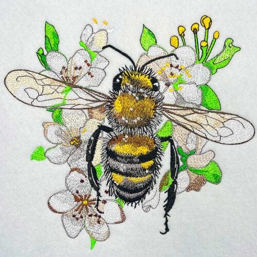 EL-Bee-1_2xl-d4ocgf | Embroidery Legacy Embroidered image of a bumble bee on white blossoms with green leaves.