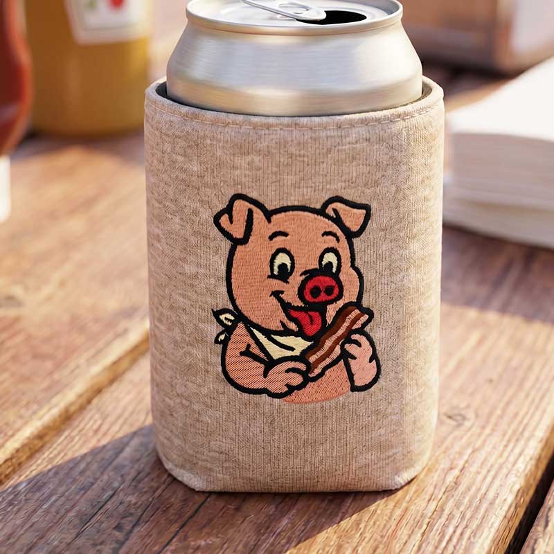 EL_CA_Pig_CanCozy | Embroidery Legacy Beige can koozie with a cartoon pig holding a hot dog on a wooden table, holding the drink upright in sunlit outdoor setting smiley pig graphic