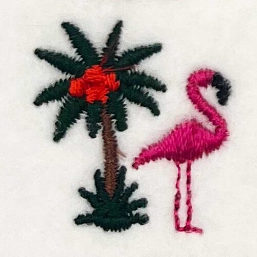 Pink embroidered flamingo standing beside a palm tree with coconuts on white fabric background
