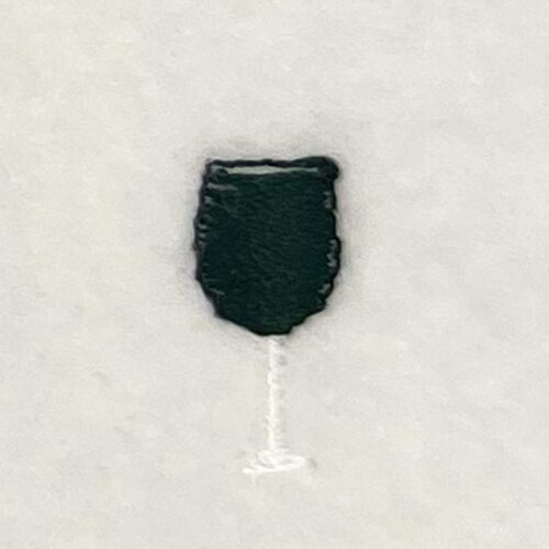 Dark green shield-shaped badge with a thin white stem on a pale background on a textured surface.