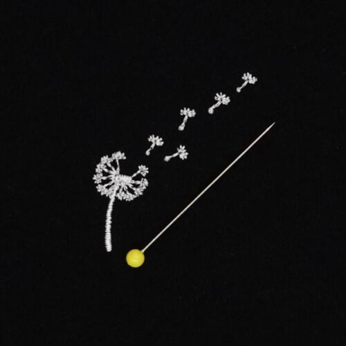 free-newsletter-design-dandi-square | Embroidery Legacy Close-up of a dandelion seed head with several seeds blown away, beside a thin pin with a yellow bead on a black background.
