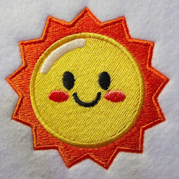 freebie-sun-square | Embroidery Legacy Smiling embroidered sun patch with a yellow face, orange rays, and rosy cheeks on light fabric.