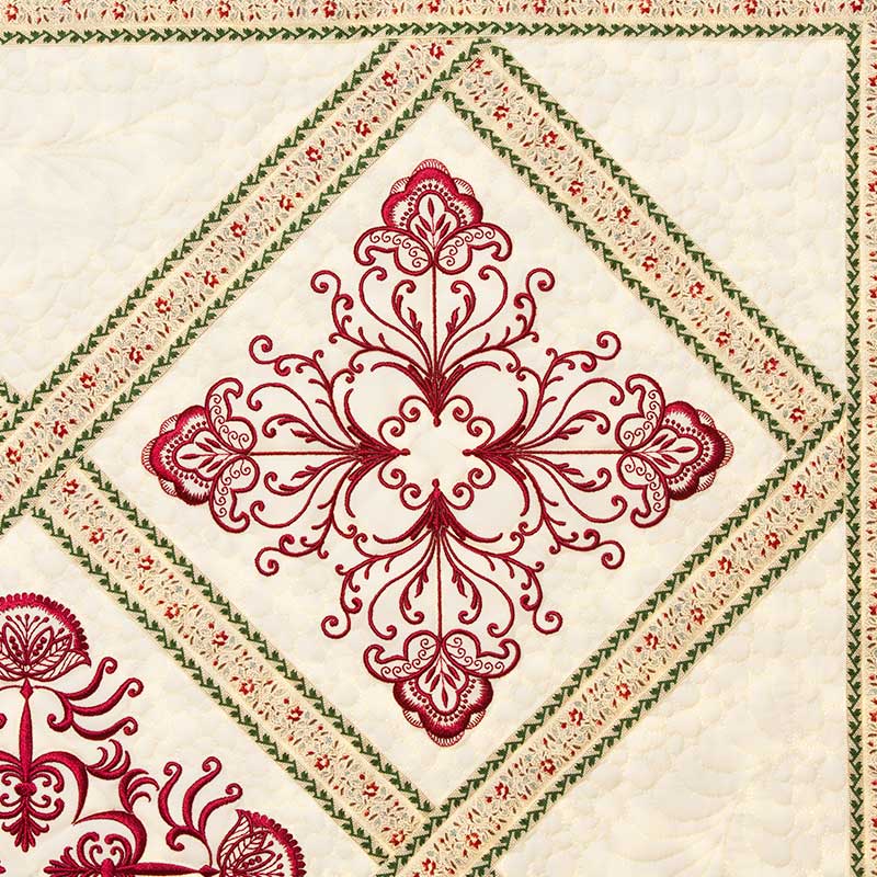 Alexa3 | Embroidery Legacy Quilt block with a red ornamental cross motif inside a diamond, bordered by green and red patterned strips on a cream background
