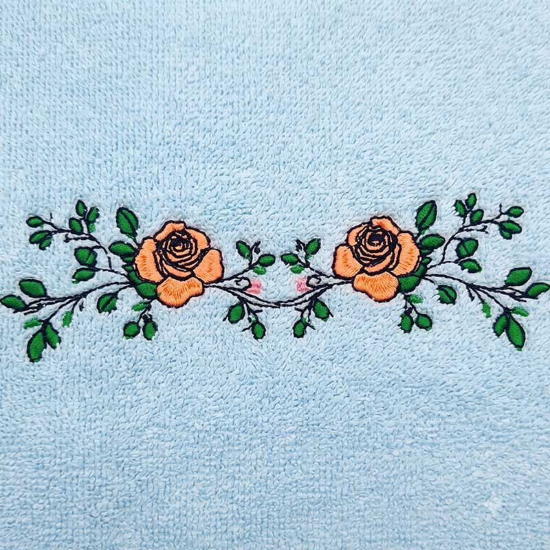 EL_FS4_c_Towel | Embroidery Legacy Light blue towel with an embroidered band of two orange roses and green leaves across the middle.