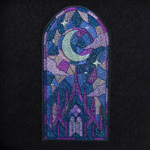 Mylar Gothic Cathedral 1 | Embroidery Legacy Colorful embroidered shield patch with geometric, jewel-toned shapes on a dark fabric background, framed by a purple border.